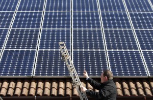 A man in Germany examines the solar panels on his roof, making power he can resell at an excellent financial return. Germany recently installed more solar cells in a single month than the United States did in all that year. (Reuters)