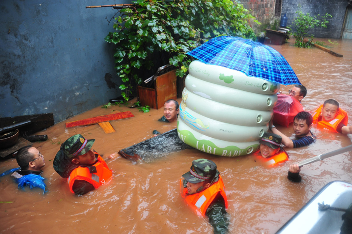 Rescuers evacuate residents carrying their possessions through the flooded streets. Getty
