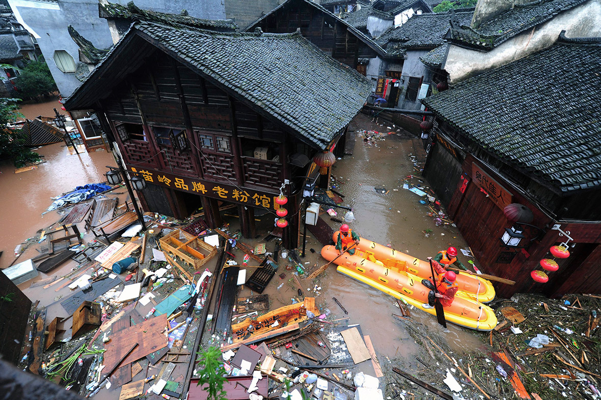 Workers clean up debris from a flooded street in the ancient town of Fenghuang. Reuters