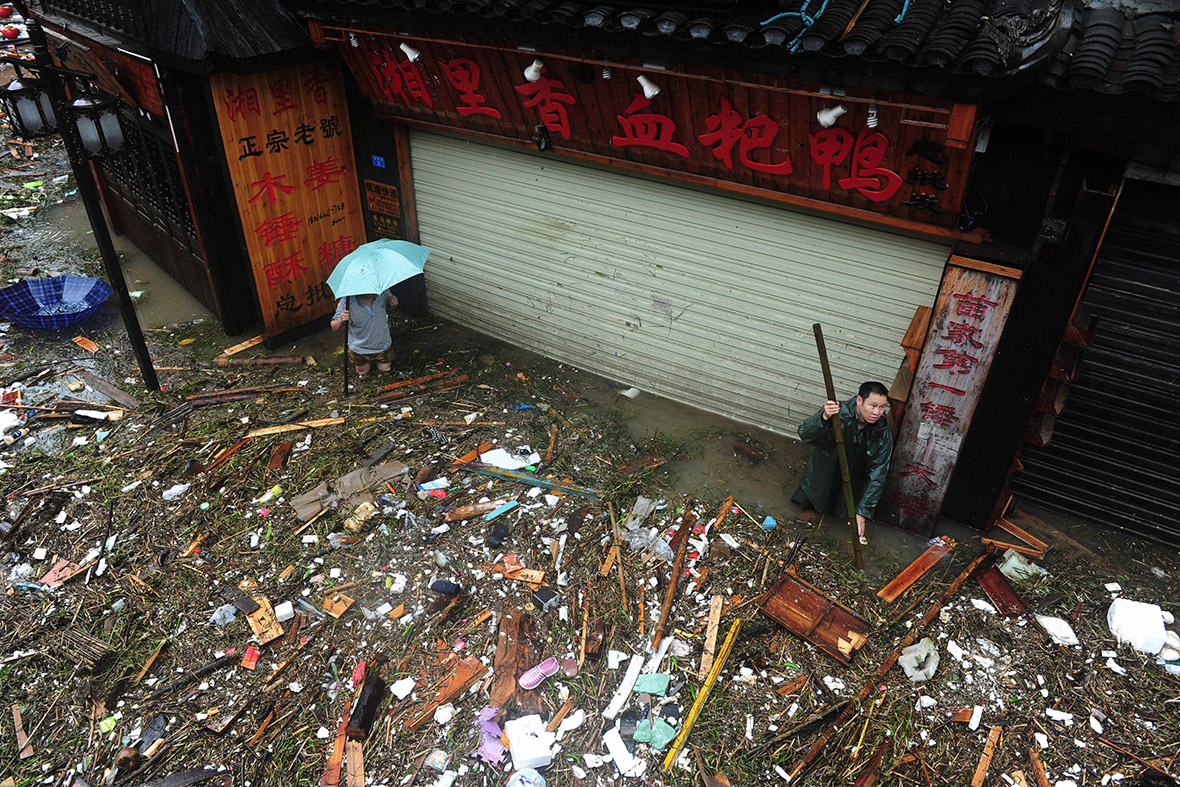 People clear debris on a flooded street in Fenghuang. Reuters